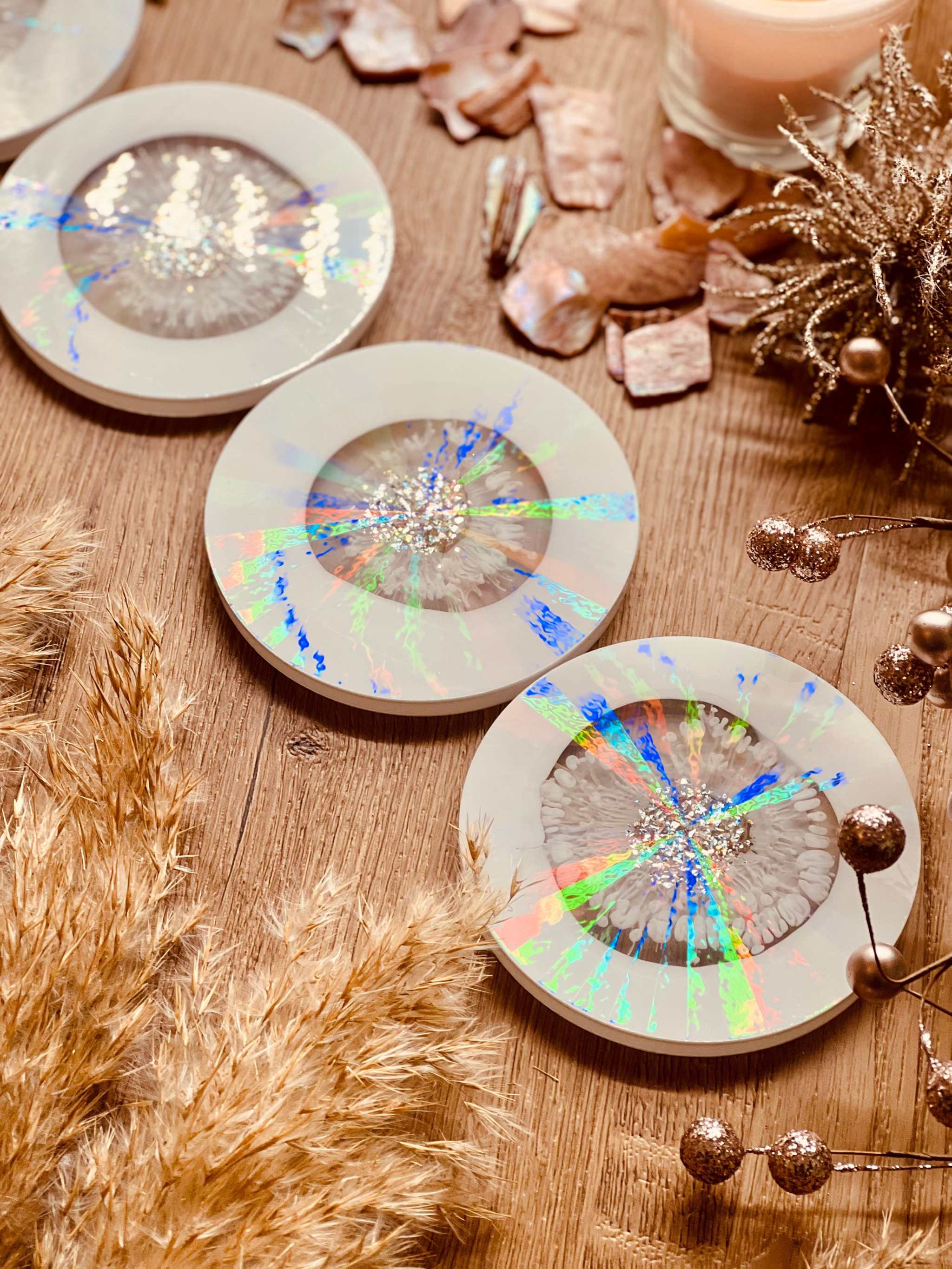 5 Untersetzer aus Resin in Weiß mit goldenen und holographischen Details auf Holztisch dekoriert