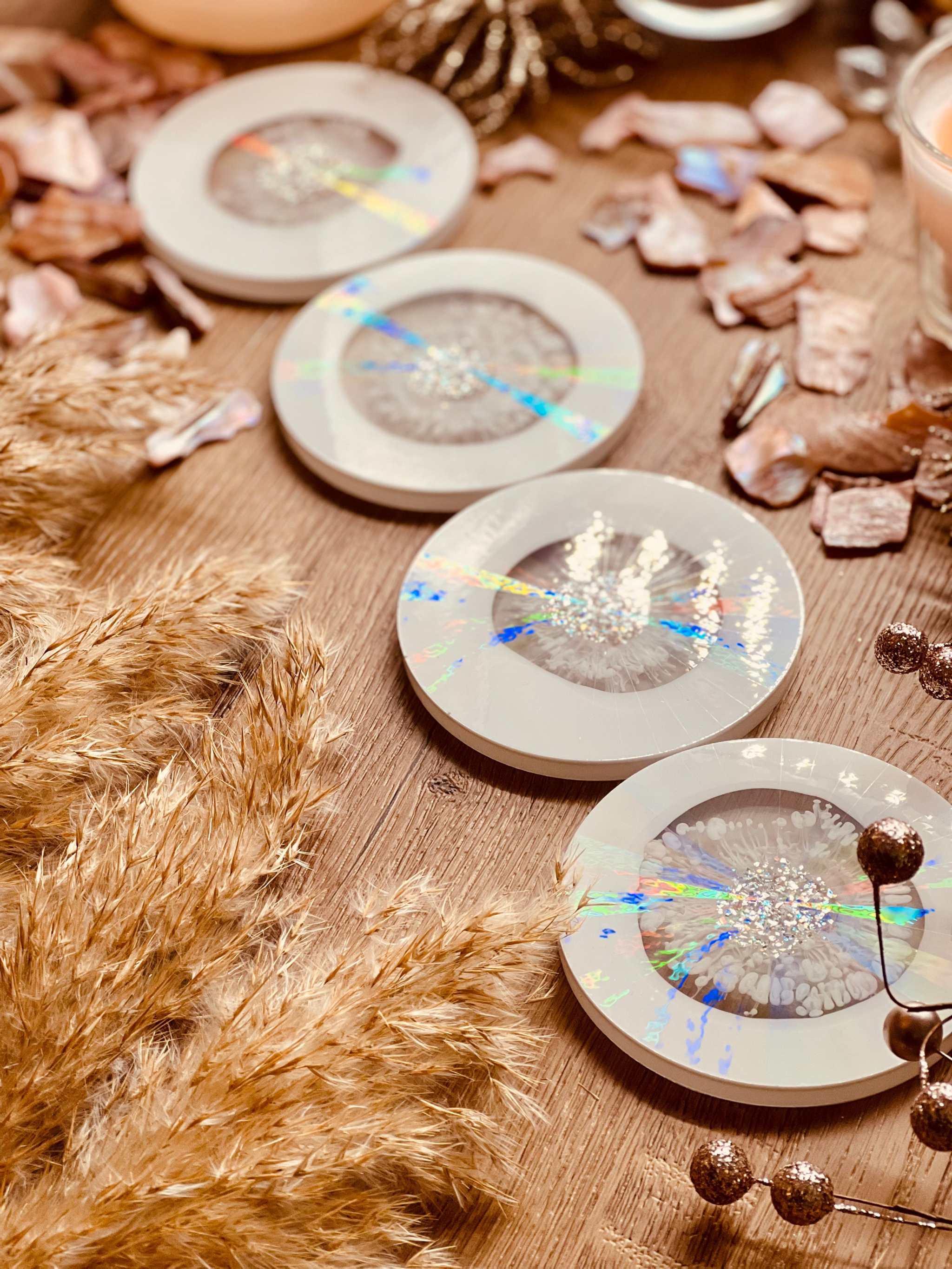 5 Untersetzer aus Resin in Weiss mit goldenen und holographischen Details auf Holztisch dekorativ angeordnet