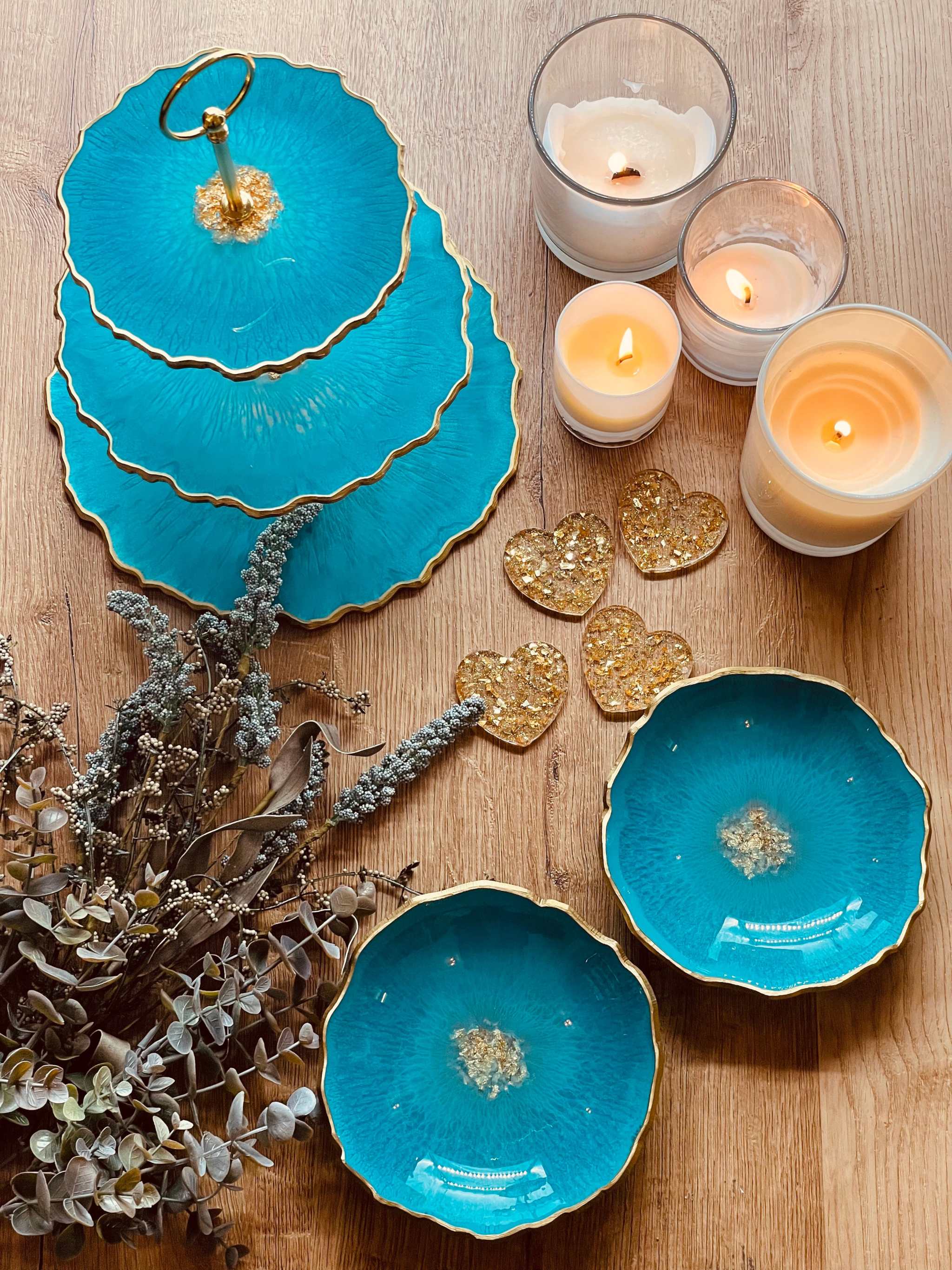 Dreistöckige handgemachte Etagere aus blauem Resin mit Goldrand auf Holztisch dekoriert mit Kerzen und Trockenblumen