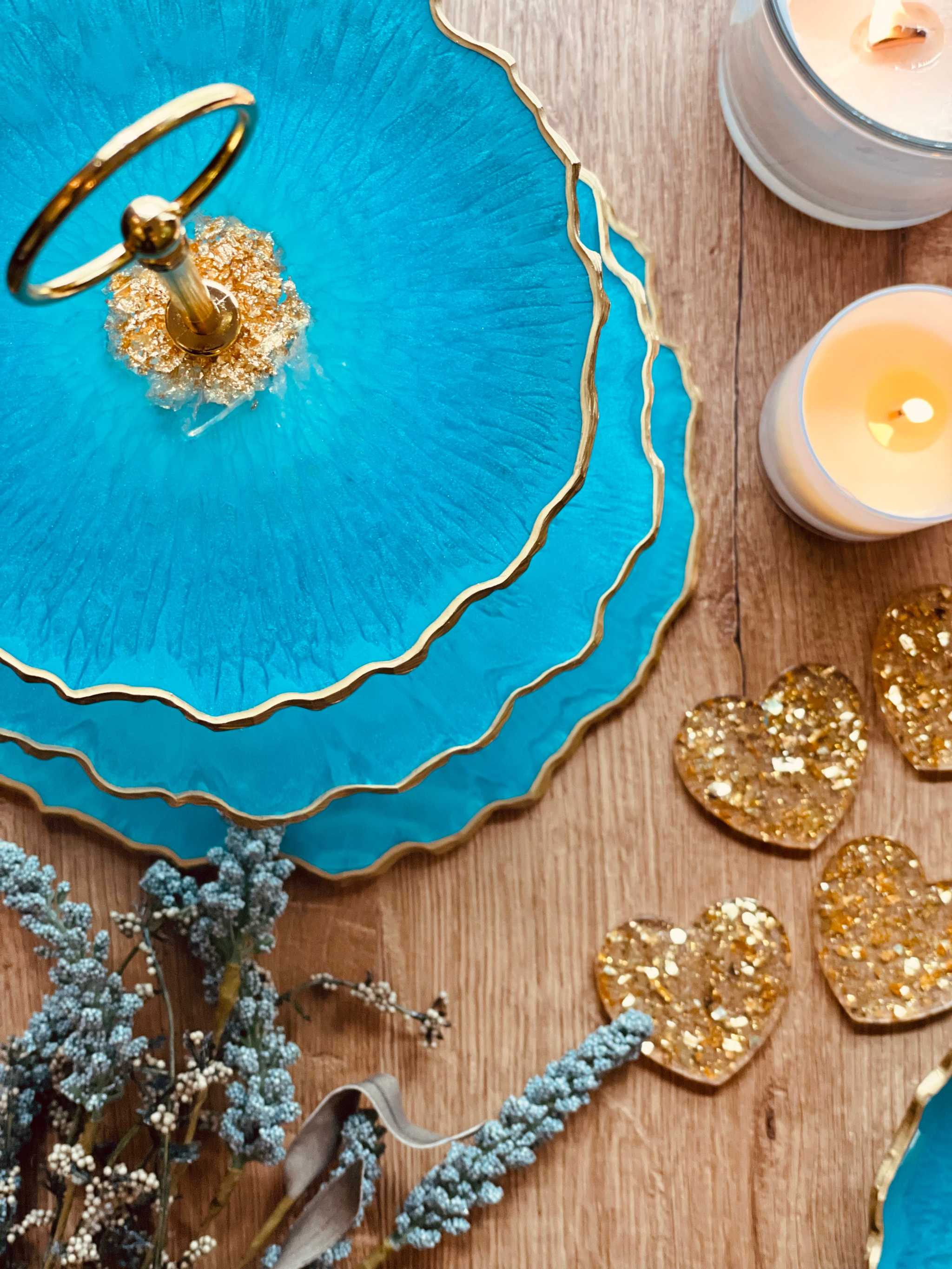 handgemachte dreistöckige eckige blaue resin etagere mit goldenen rändern und dekorativen kerzen und glitzerherzen auf holztisch