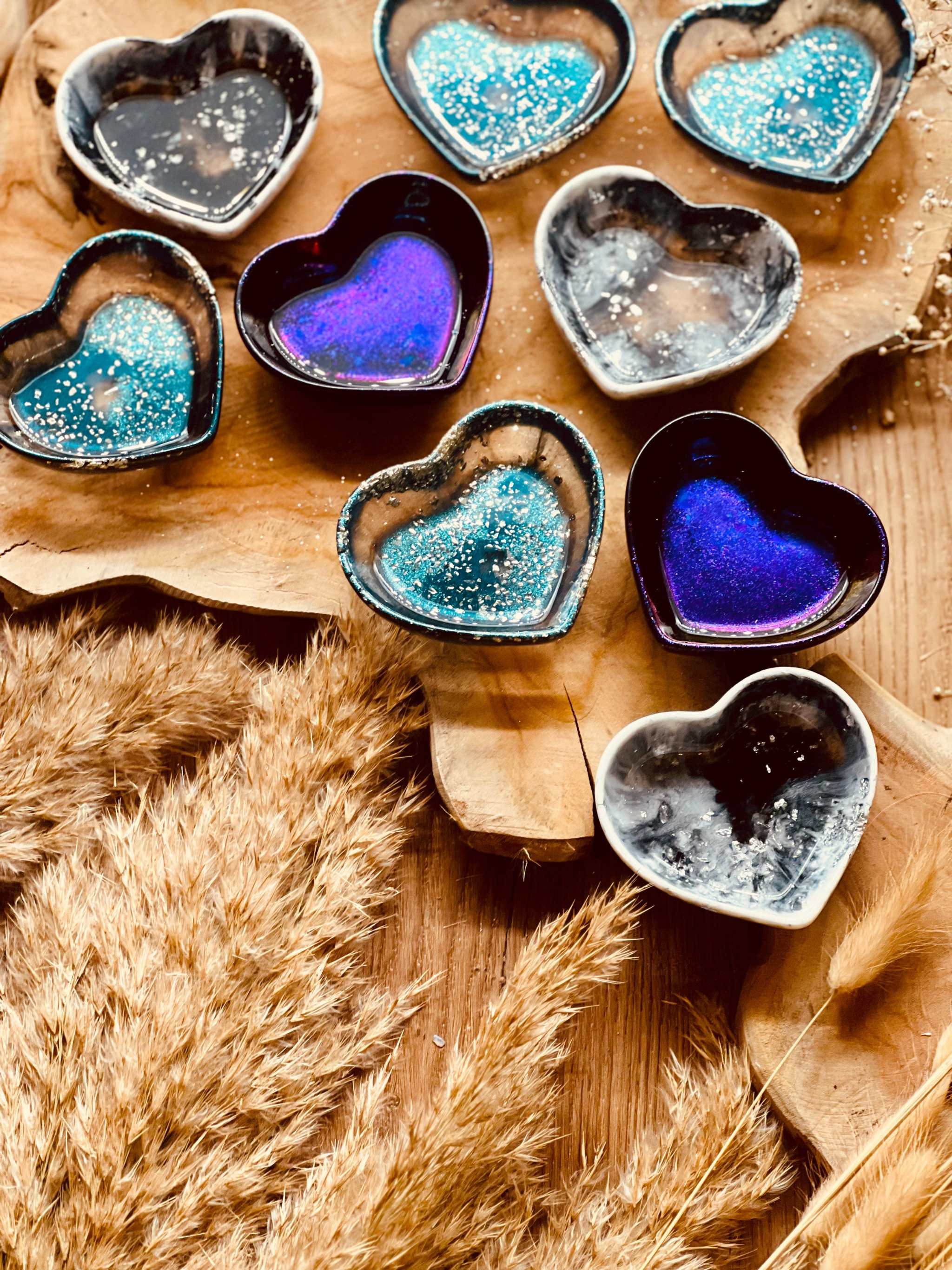 Herzförmige Schmuckschalen aus Resin in verschiedenen Farben, handgemacht und einzigartig, auf Holztisch platziert