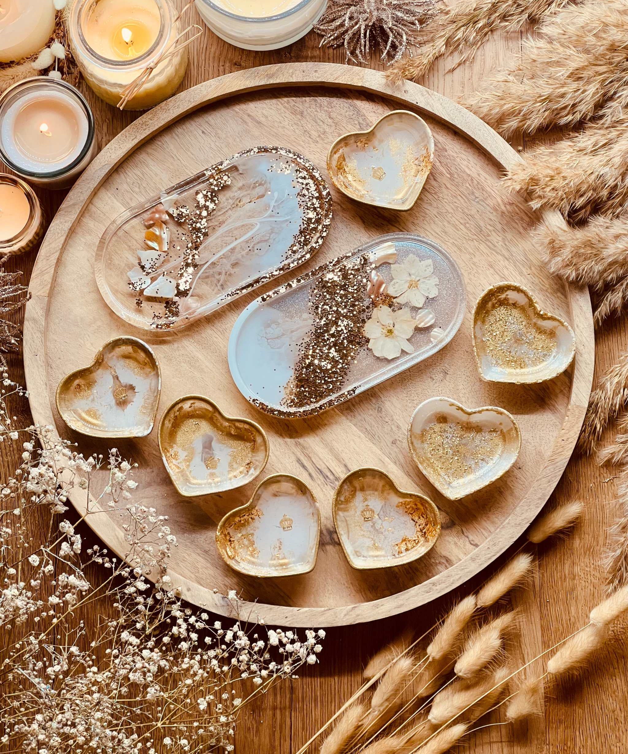 Handgemachte weiße Schmuckschalen aus Resin mit goldenen Details, Perlmutt und Blumen in Herz- und Ovalformen auf Holztablett