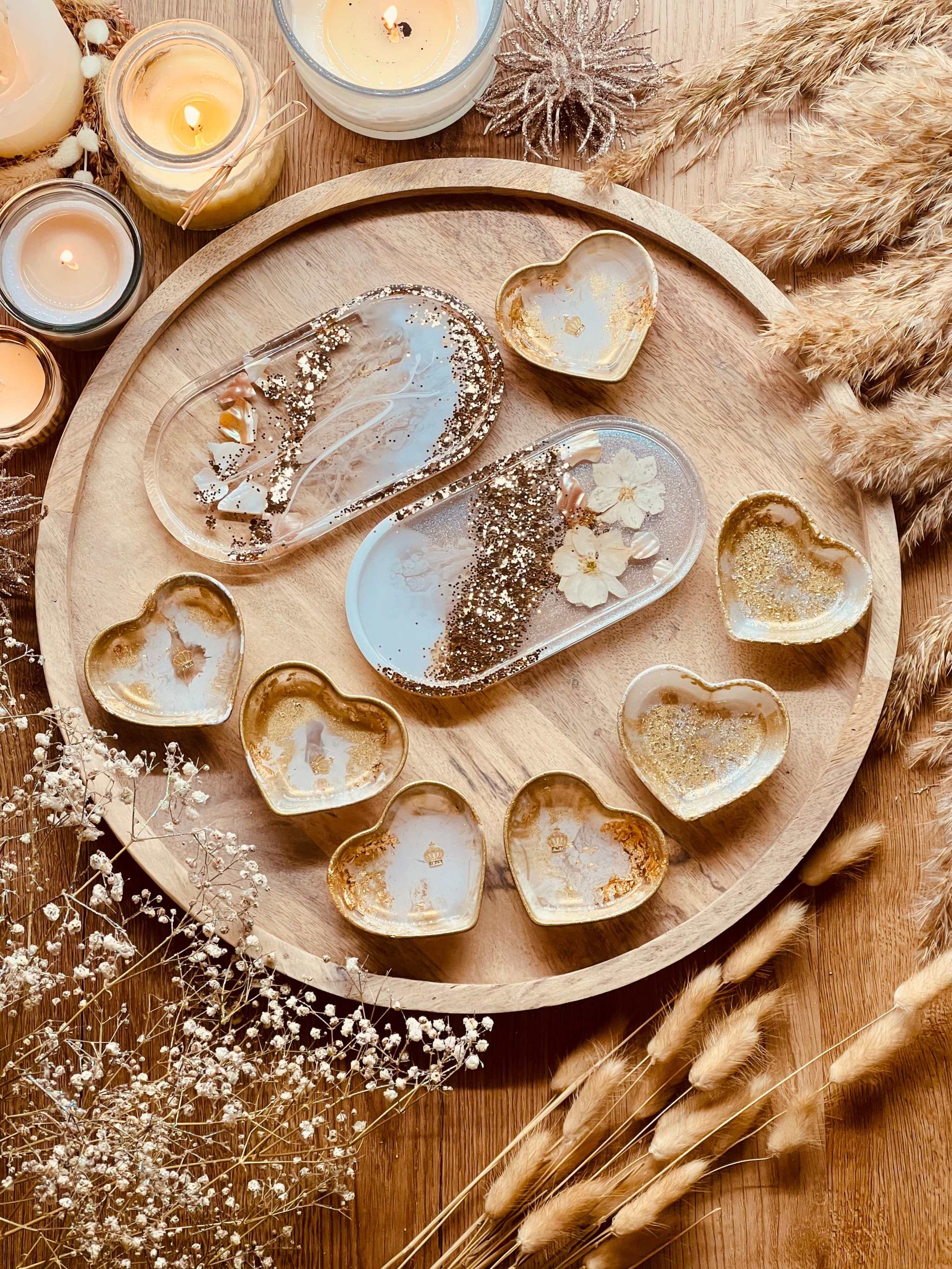 Handgemachte weiße Schmuckschalen aus Resin mit goldenen Details, Perlmutt und Blumen in Herz- und Ovalformen auf Holztablett