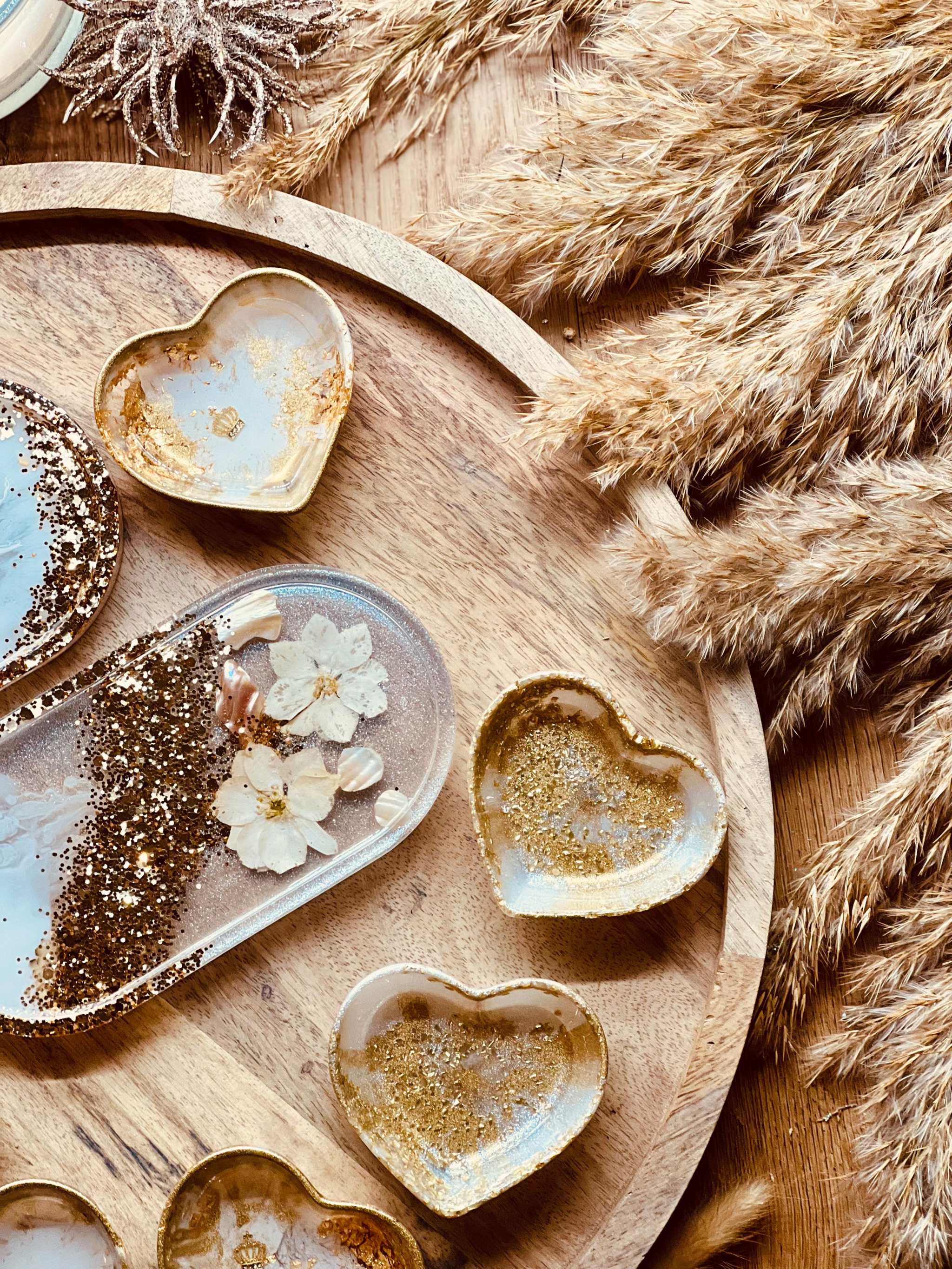 Schmuckschalen aus Resin in Weiß mit goldenen Details, Perlmutt und getrockneten Blumen als handgemachte Unikate auf rundem Holztablett