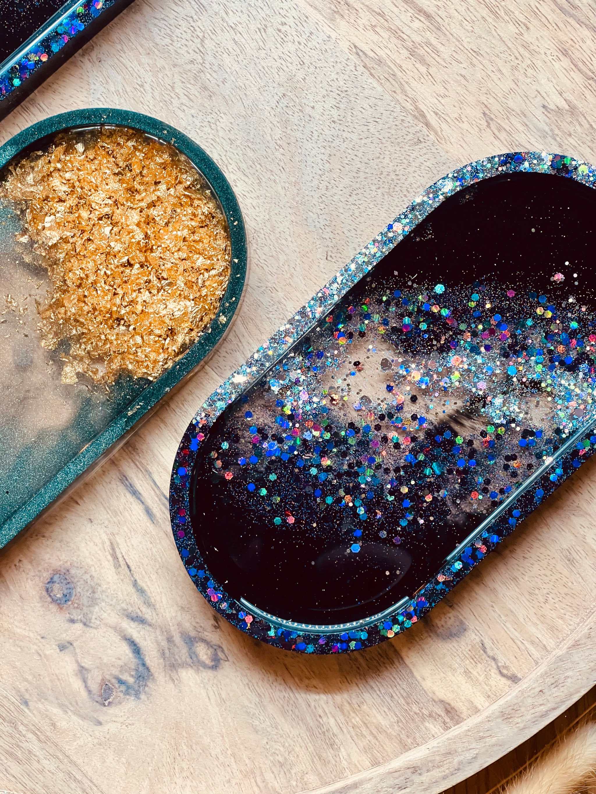 Handgemachte Schmuckschalen aus Resin in grün mit goldenen Details und holographisch schwarz auf Holzuntergrund