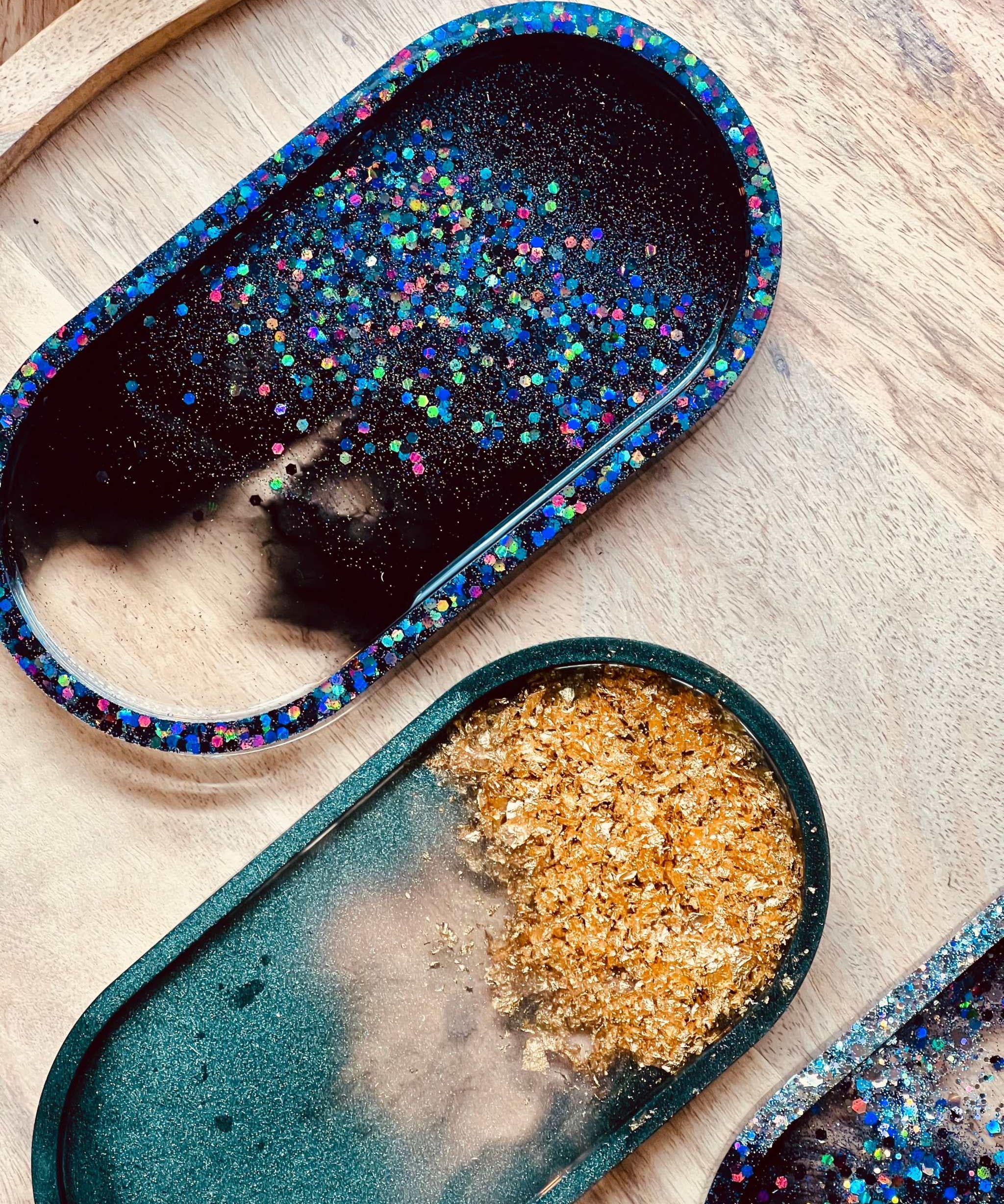 Schmuckschalen aus Resin in grün mit goldenen Details und holographisch schwarz als handgemachte Unikate auf Holzplatte