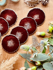 Handgemachte rote Untersetzer aus Resin in einzigartigem Design auf Holztisch mit Dekoration