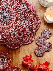 rote handgemachte Mandala Etagere aus Resin mit vier passenden Untersetzern und dekorativen Kerzen auf Holztisch