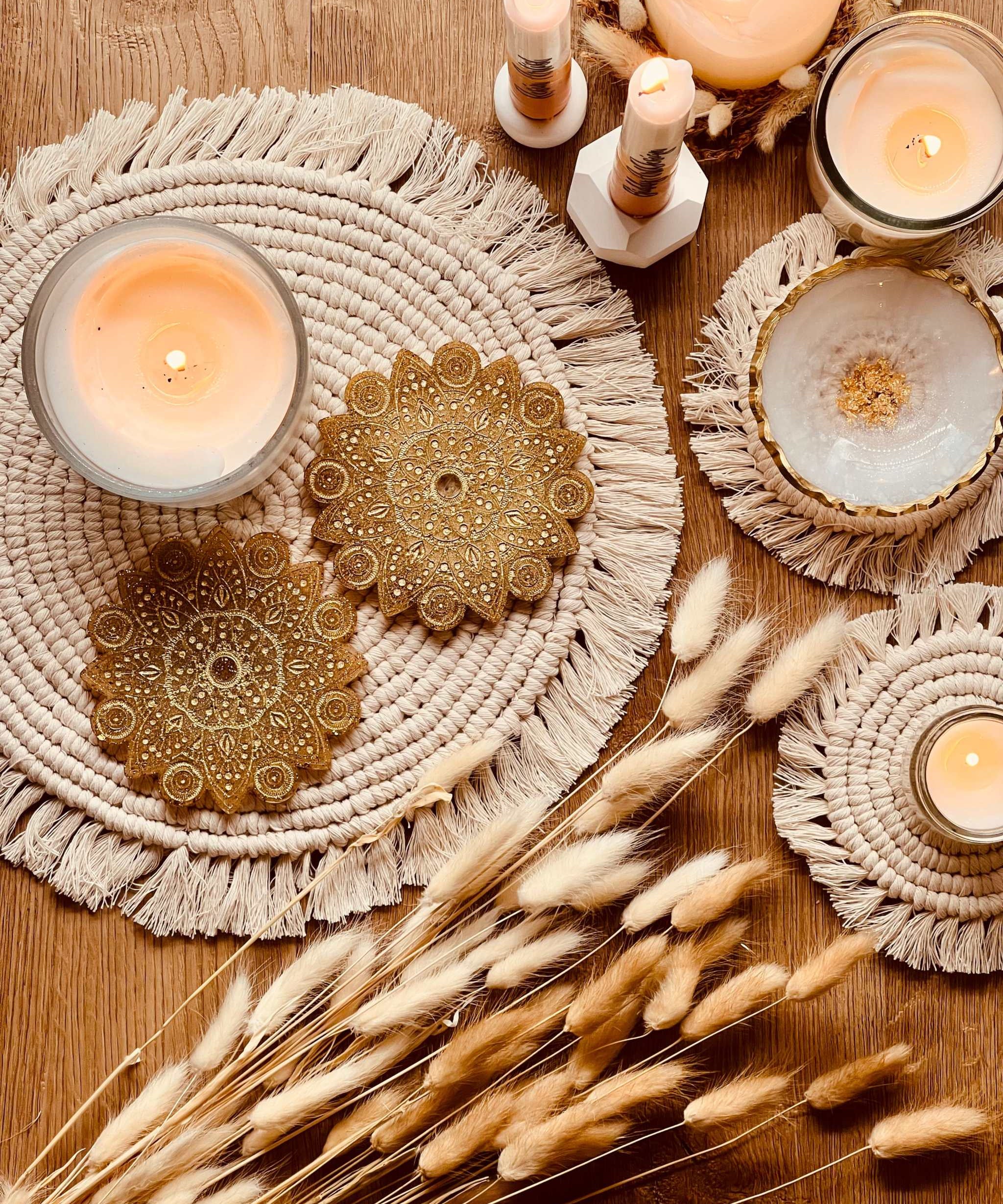 2 handgemachte Mandala Untersetzer aus goldfarbenem Resin auf einem Boho-Tisch mit Kerzen und Trockenblumen