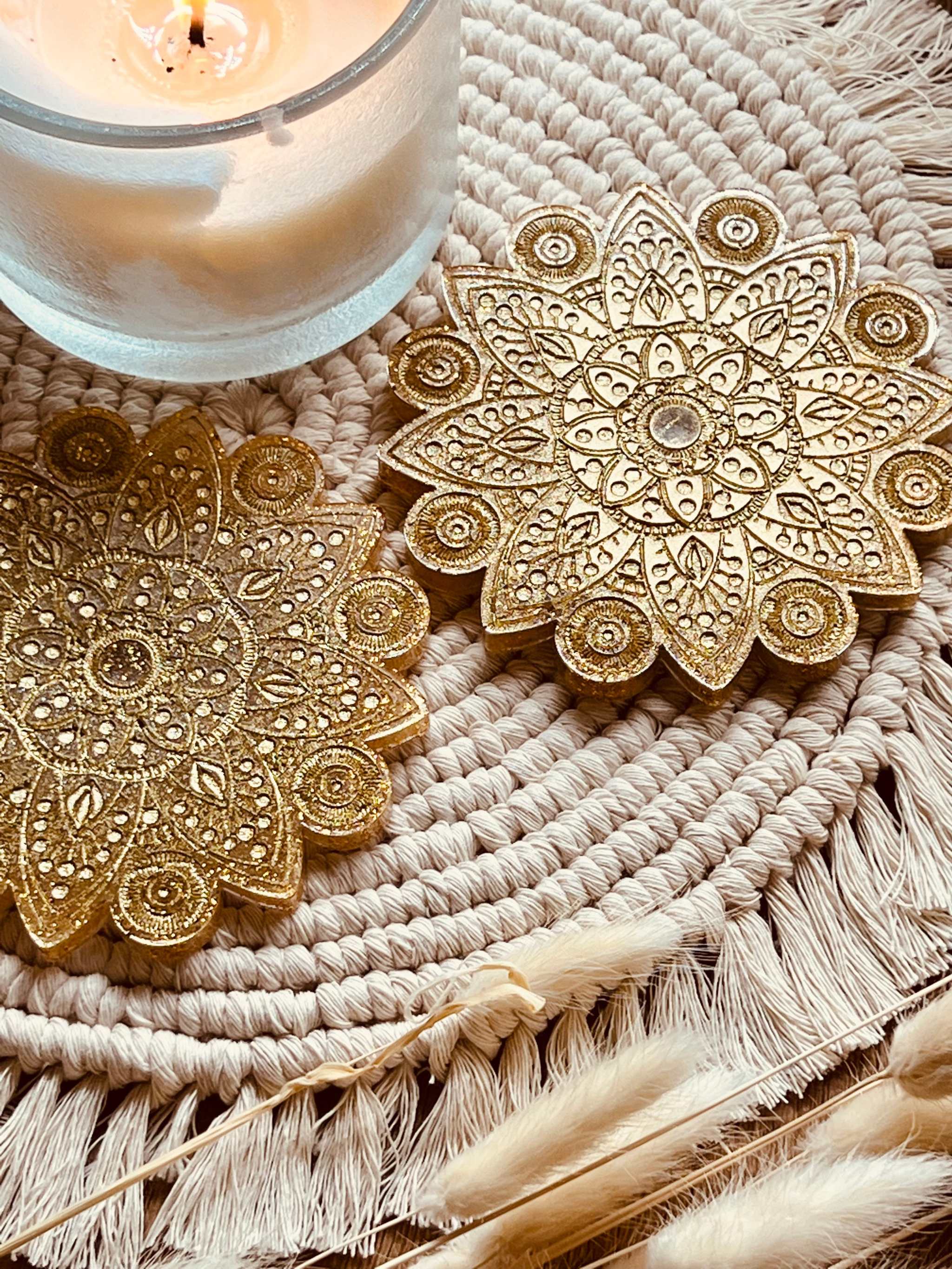 2 handgemachte goldene Mandala Untersetzer aus Resin auf dekorativem Stoff mit Kerze