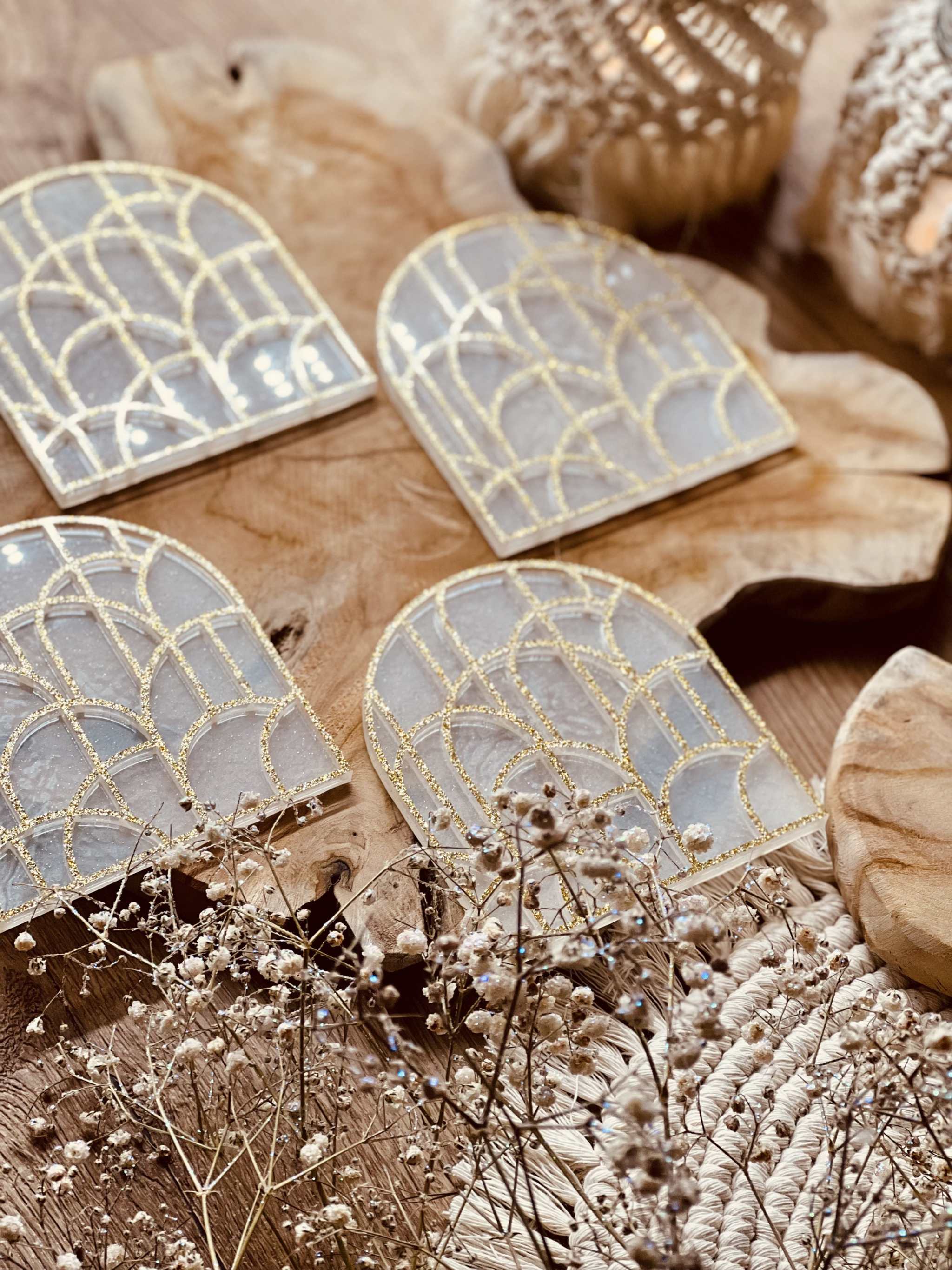 4 geometrische Untersetzer aus weiss-goldenem Resin mit 3D Design auf Holztisch