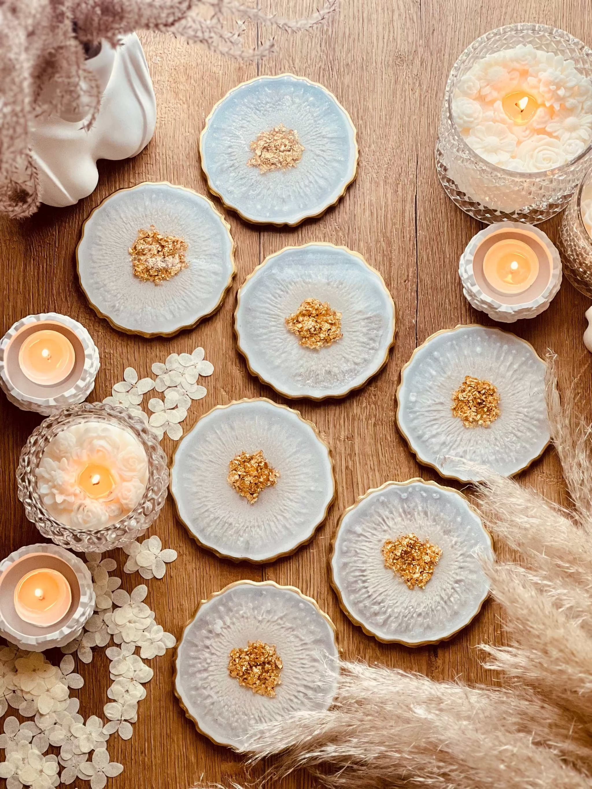 7 klassische Untersetzer aus weißem Resin mit goldenen Details und Ø 12 cm auf Holztisch mit Kerzen und Dekoration