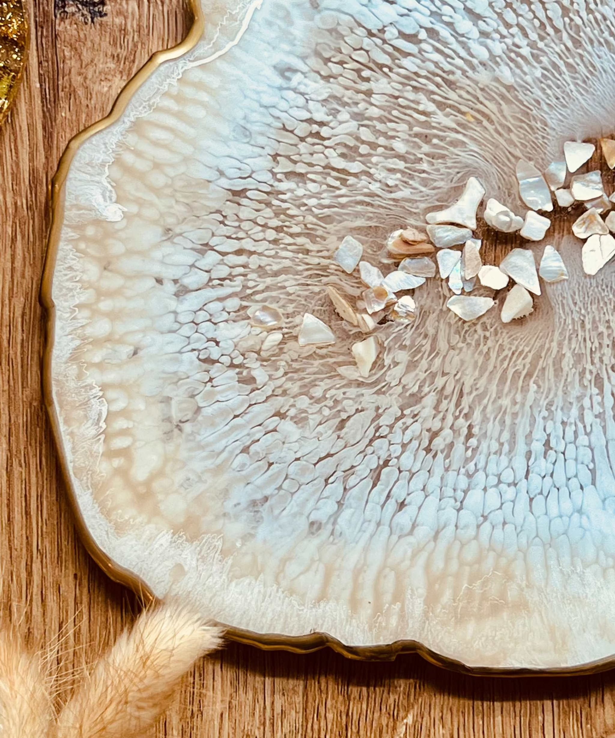 Beiges handgemachtes Tablett aus Resin mit goldenen Details und Perlmutt auf Holztisch