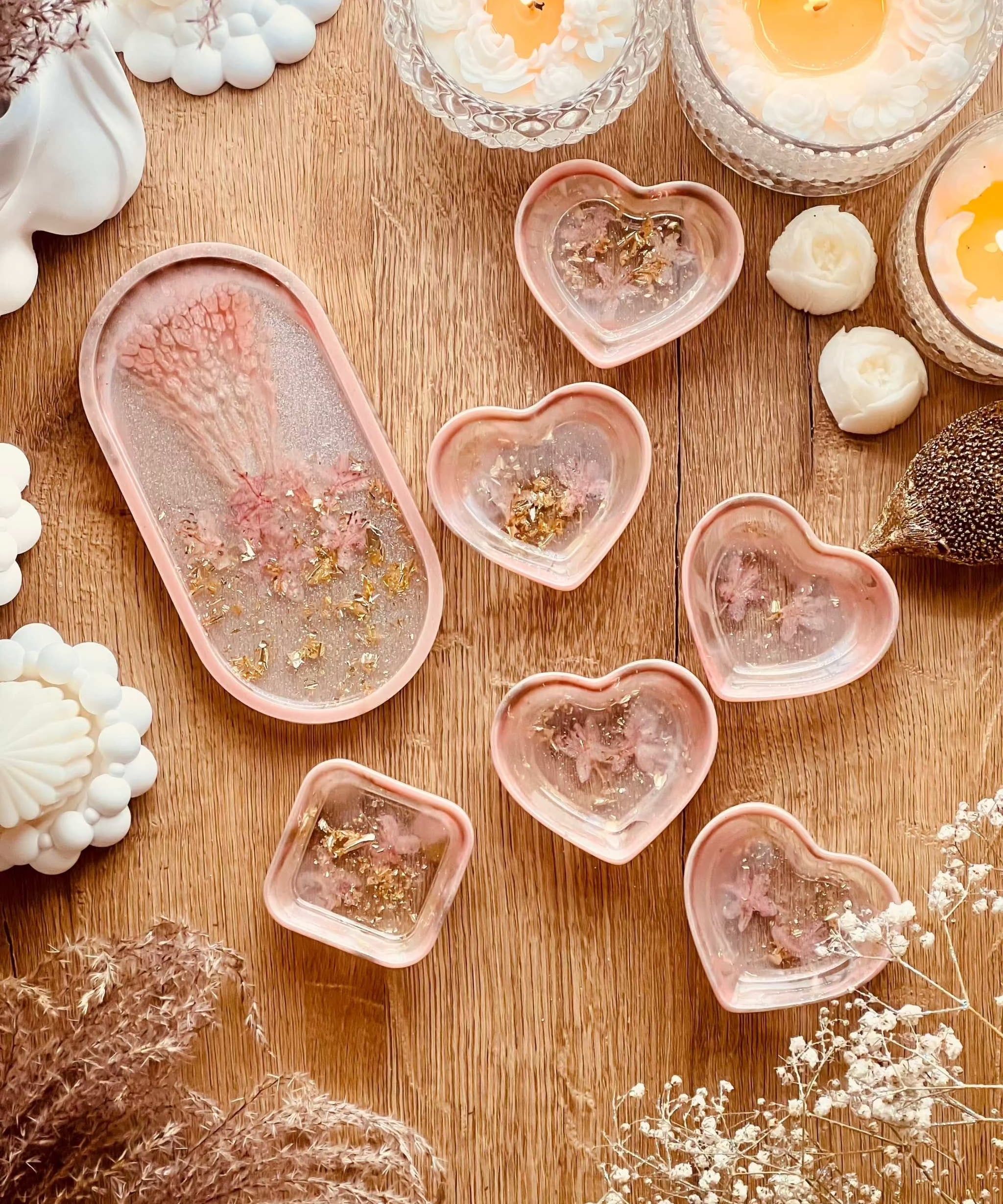 Handgefertigte Schmuckschalen aus Resin in Korall mit Gold und getrockneten Rhododendron Blüten auf Holztisch mit Kerzen und Dekoration