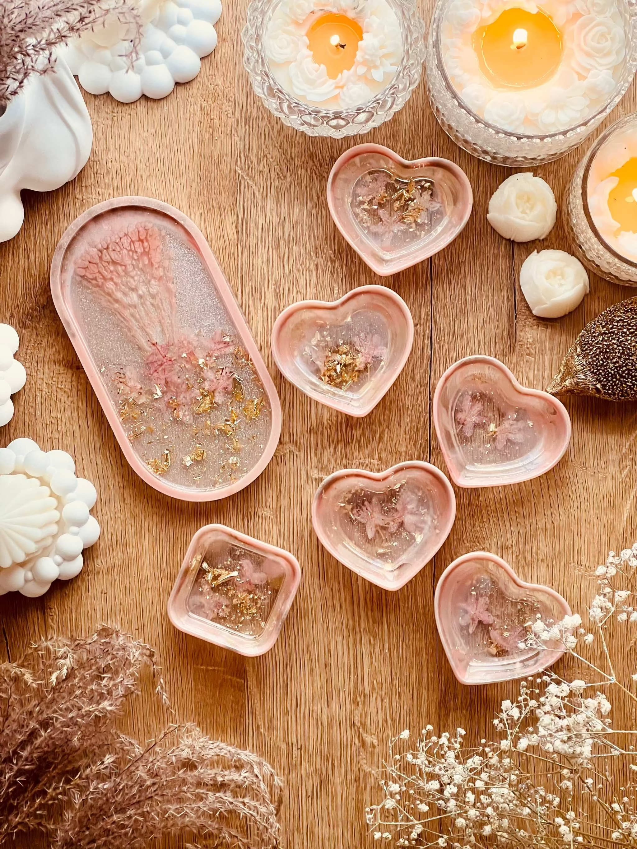 Handgefertigte Schmuckschalen aus Resin in Korall mit Gold und getrockneten Rhododendron Blüten auf Holztisch mit Kerzen und Dekoration