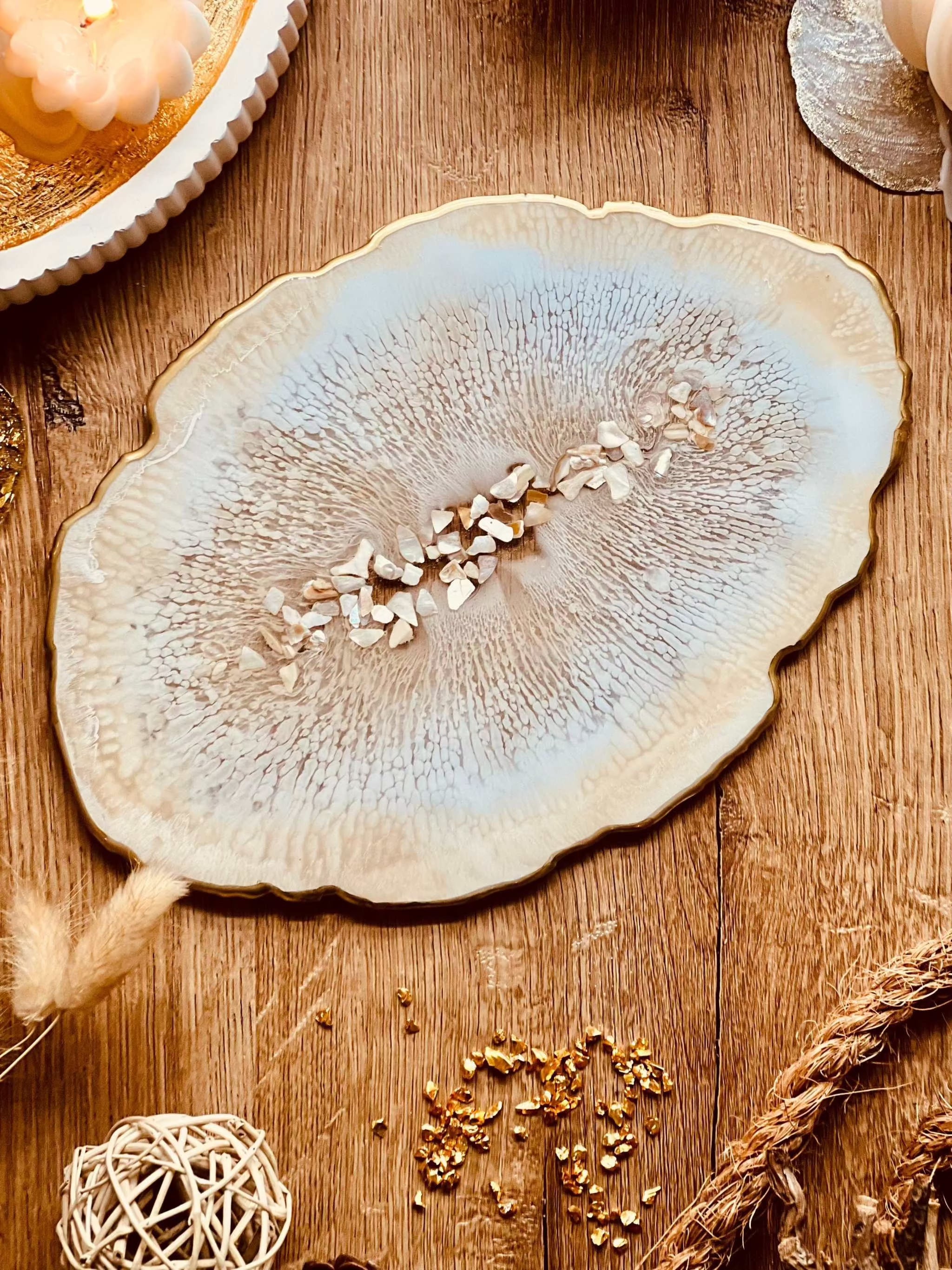 Beige handgemachtes Tablett aus Resin mit goldenen Details und Perlmuttstücken auf Holztisch