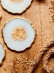 weiße Untersetzer aus Resin mit goldenen Details im 4er Set auf Holztisch