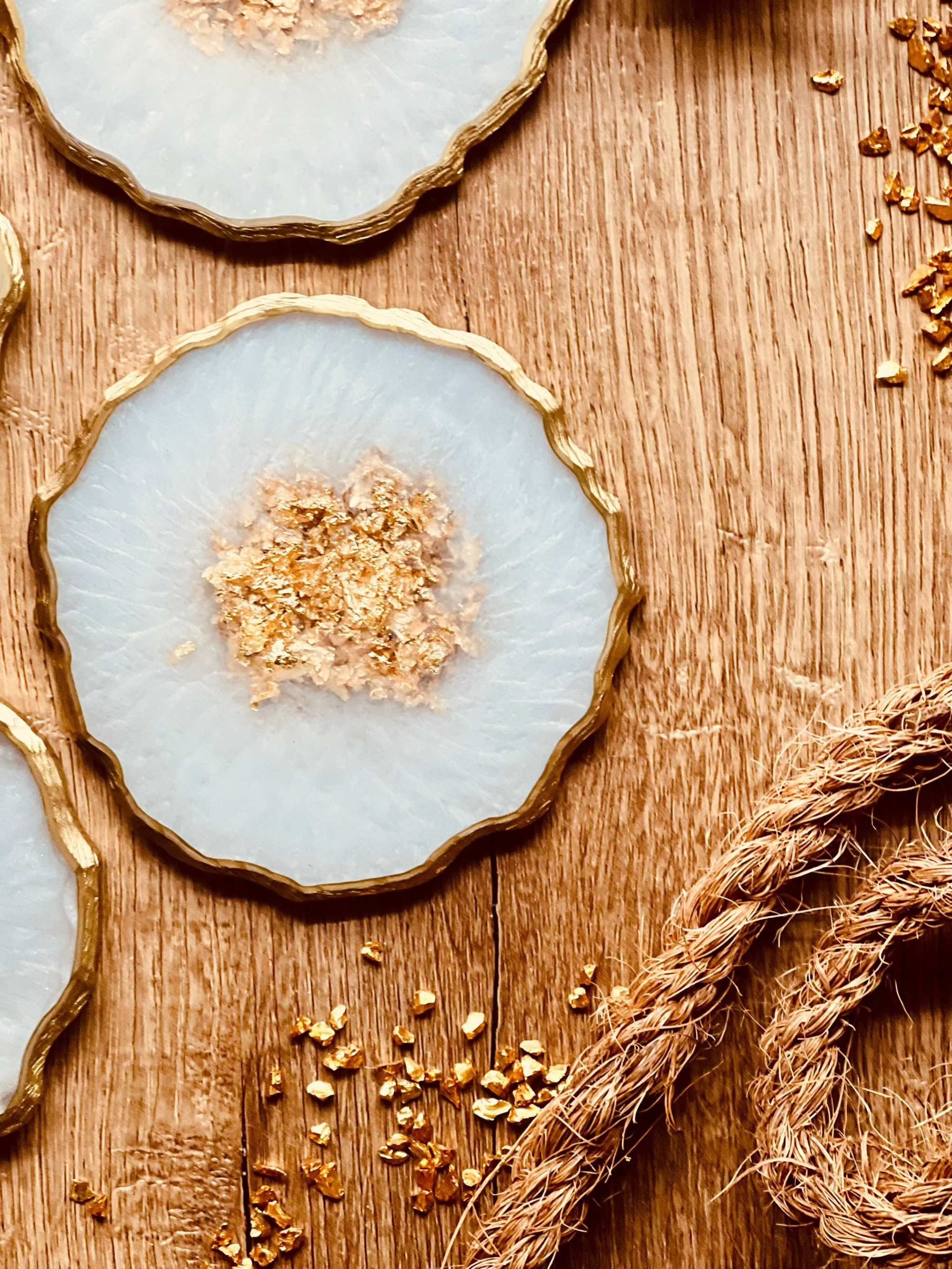 weiße Untersetzer aus Resin mit goldenen Details im 4er Set auf Holztisch