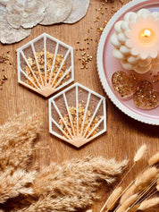 2 außergewöhnliche handgemachte Untersetzer aus weißem Resin mit goldenen Details auf Holztisch dekorativ platziert