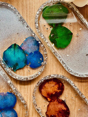 Handgemachte Schmuckschalen aus Resin mit Silberrand und farbigen Rosenblättern auf Holztisch