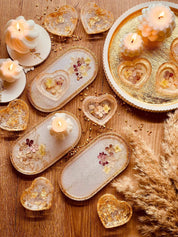 Handgefertigte weiße Schmuckschalen aus Resin mit Gold und getrockneten Blumen, dekorativ auf Holz und goldenem Tablett arrangiert.