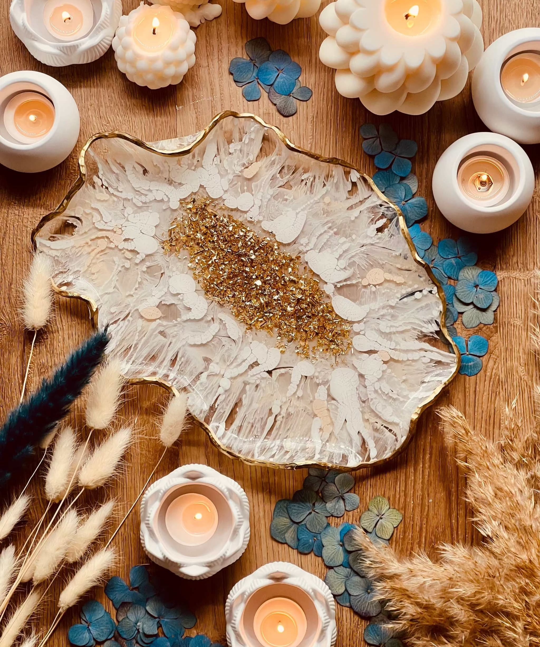 Handgemachte weiße Resin Schale mit goldenen 3D Details als dekoratives Tablett auf Holztisch umgeben von Kerzen und Trockenblumen