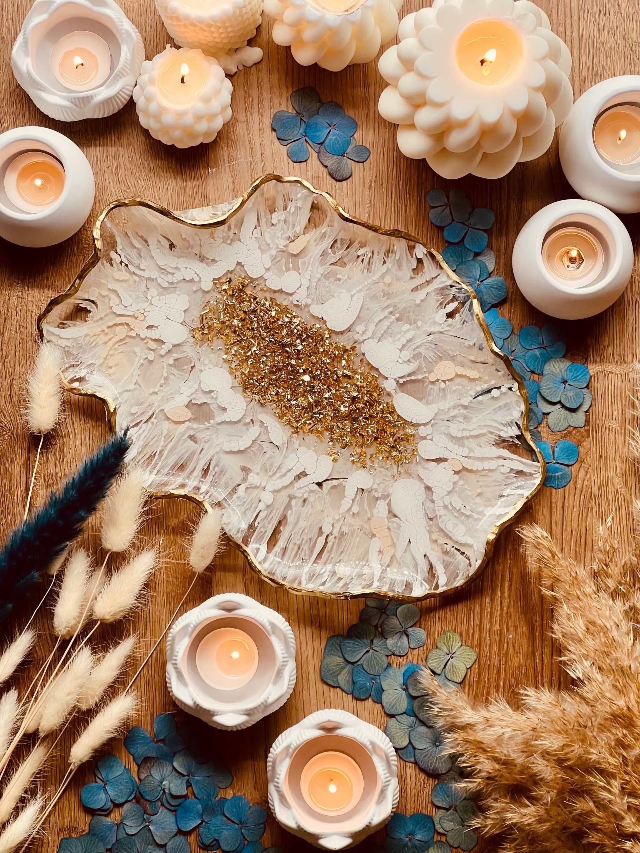 Handgemachte weiße Resin Schale mit goldenen 3D Details als dekoratives Tablett auf Holztisch umgeben von Kerzen und Trockenblumen