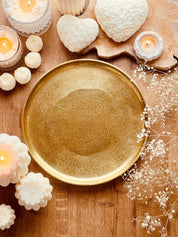 rundes goldenes Metalltablett The low mit Kerzen und Dekoration auf Holztisch