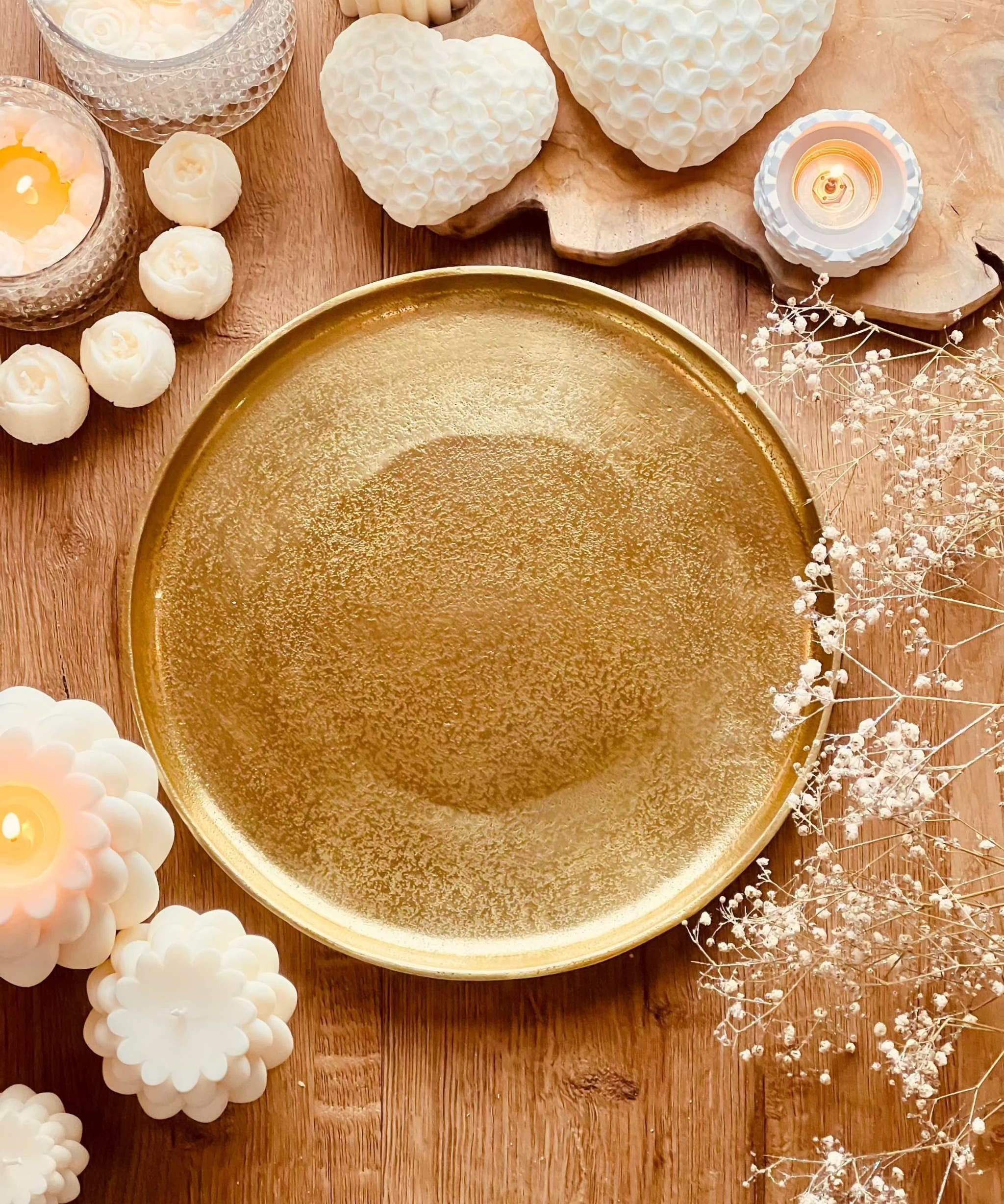 rundes goldenes Metalltablett The low mit Kerzen und Dekoration auf Holztisch