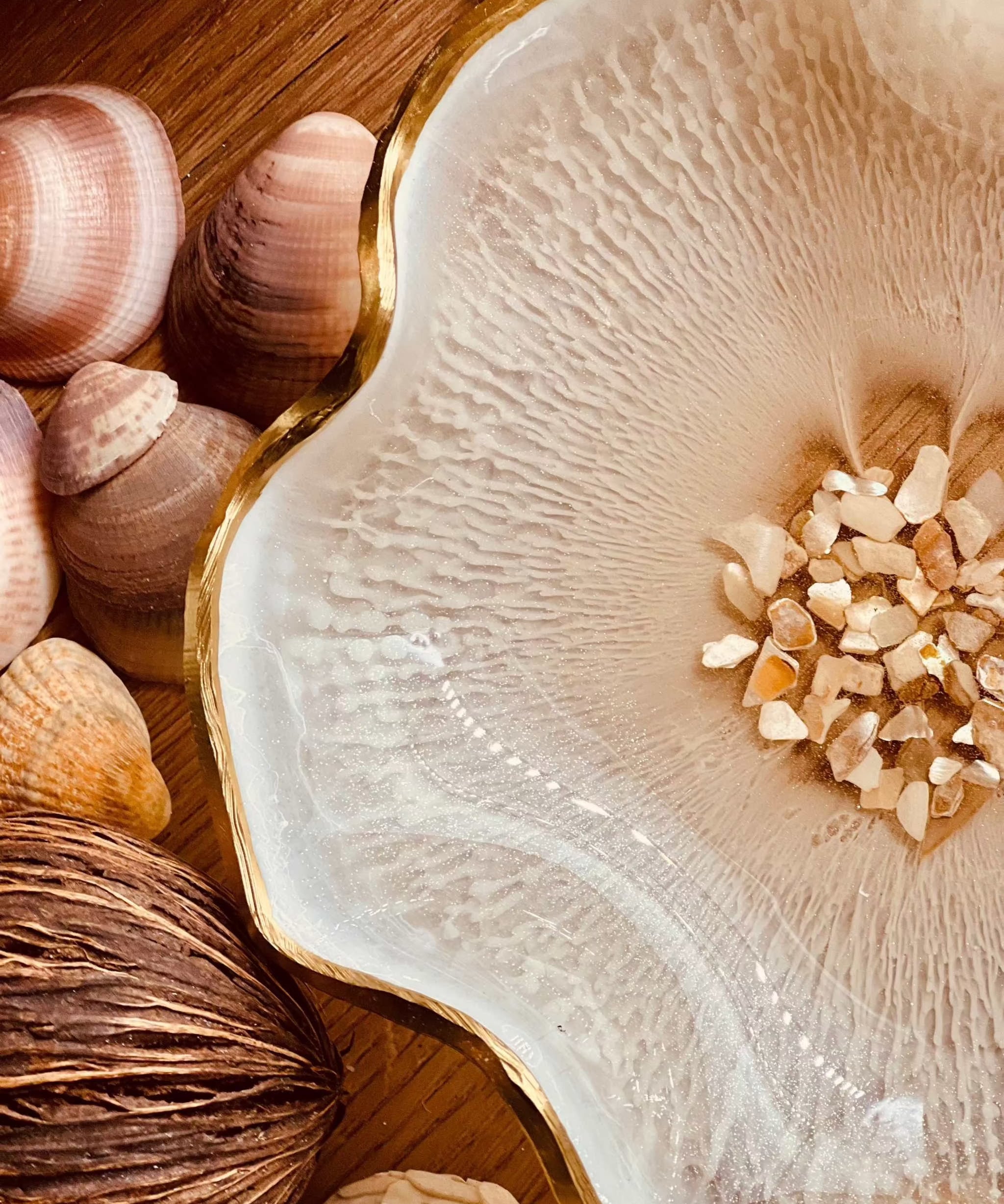 Weiße handgemachte Schale aus Resin mit Perlmutt und Goldrand, dekorativ auf Holz mit Muscheln arrangiert