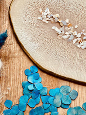 Handgemachtes beiges Tablett aus Resin mit goldenen Details und Perlmutt auf Holztisch mit blauen Blumen