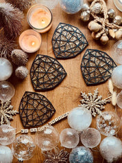 Schwarze handgemachte Untersetzer aus Resin mit goldenen 3D-Details im 4er Set auf Holztisch mit Weihnachtsdekoration