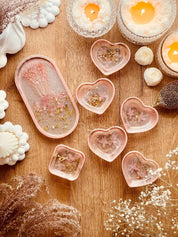 Handgemachte Schmuckschalen aus Resin in Korall mit Gold und getrockneten Rhododendronblüten auf Holztisch