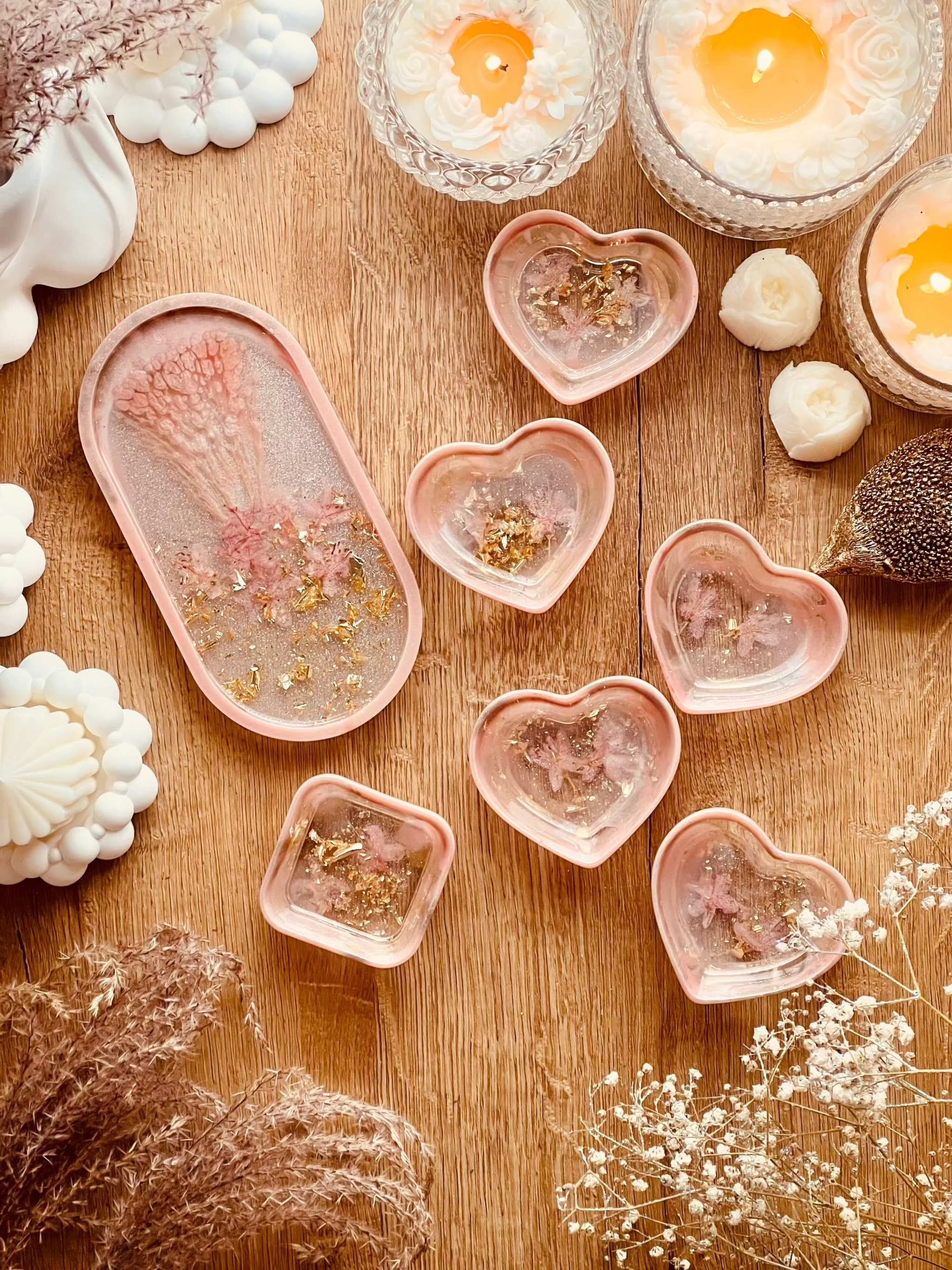 Handgemachte Schmuckschalen aus Resin in Korall mit Gold und getrockneten Rhododendronblüten auf Holztisch