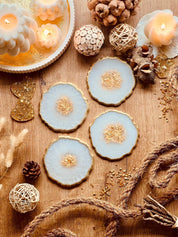 4 handgemachte Untersetzer aus Resin in weiss mit goldenen Details auf Holztisch dekoriert