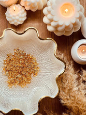 Handgemachte Schale aus Resin in Weiß mit goldenen Details und dekorativen Kerzen auf Holztisch