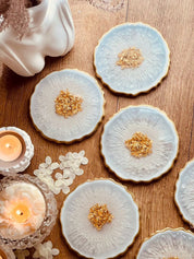 7 klassische Untersetzer aus weiss-goldenem Resin mit handgemachten Details auf Holztisch