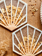 2 außergewöhnliche weiße Resin-Untersetzer mit goldenen Details im 2-teiligen Set auf Holztisch