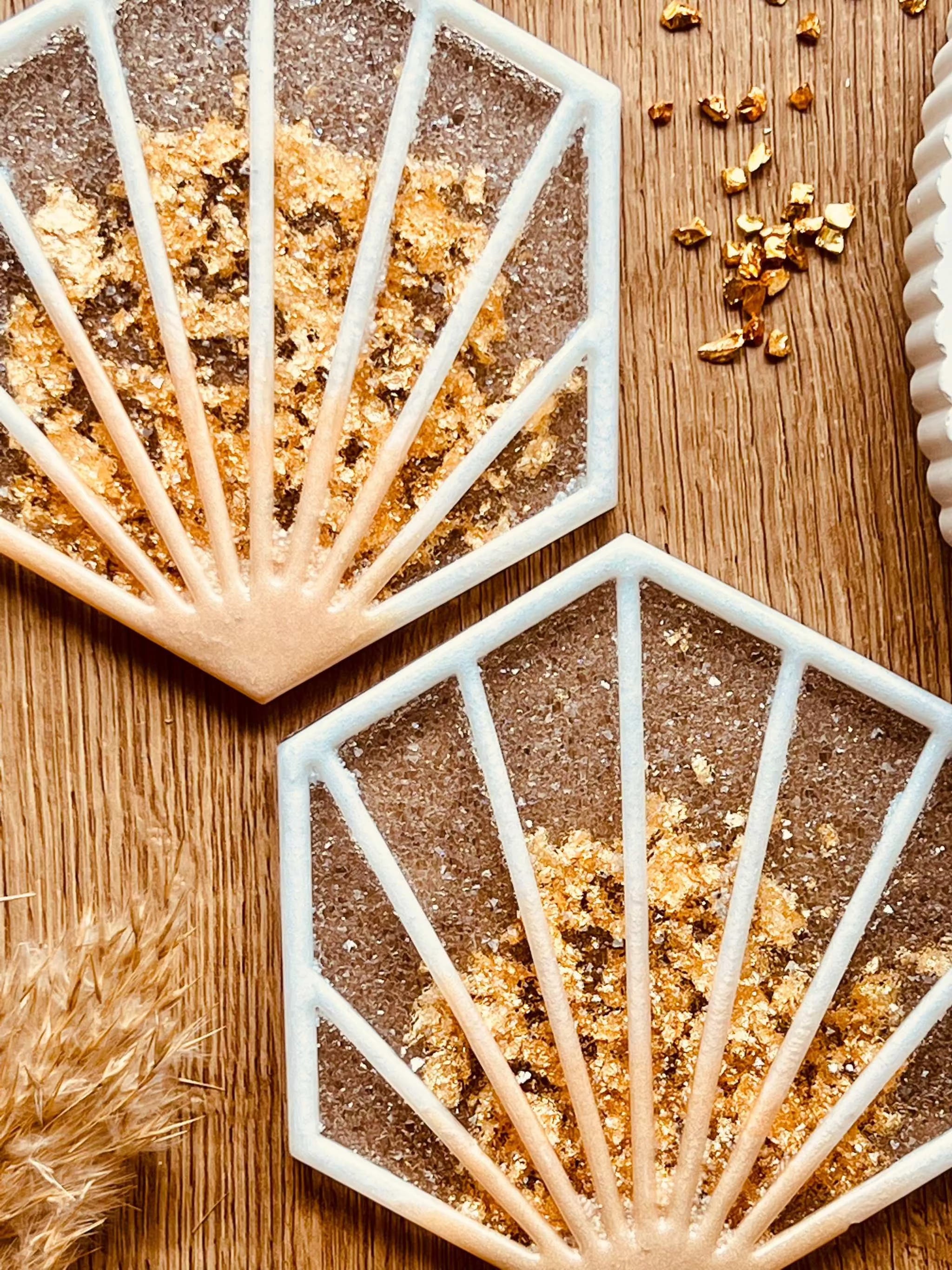 2 außergewöhnliche weiße Resin-Untersetzer mit goldenen Details im 2-teiligen Set auf Holztisch