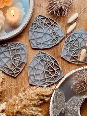 Set aus 4 handgemachten weißen Resin Untersetzern mit silbernen Details auf Holztisch