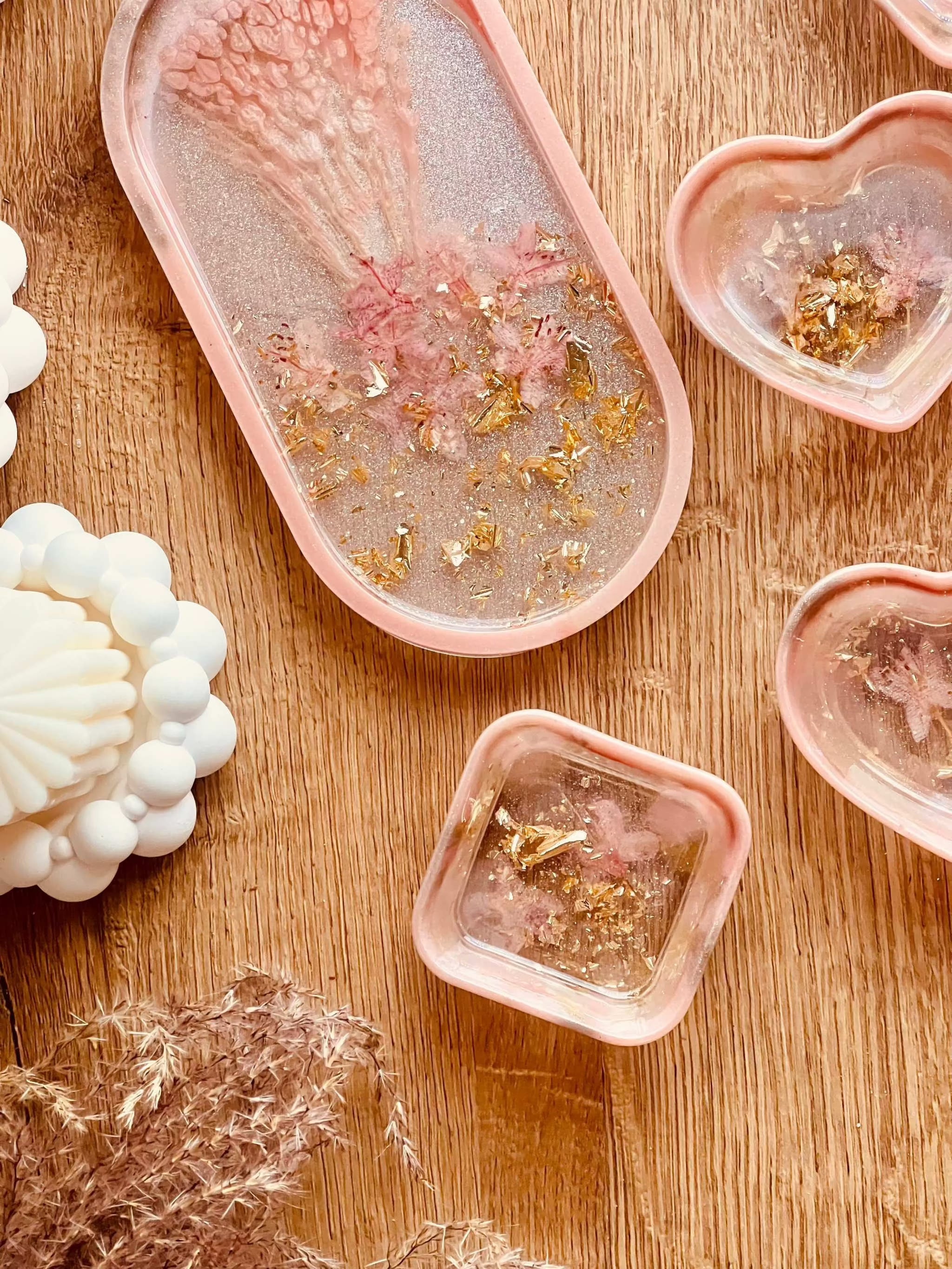 Handgemachte Schmuckschalen aus Resin in Korall mit Gold und getrockneten Rhododendron Blüten, verschiedene Formen auf Holztisch